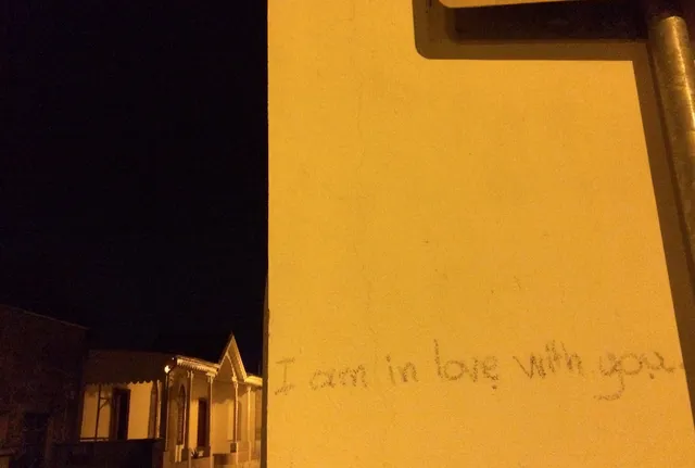 Η φράση «I am in love with you» γραμμένη χαμηλά σε κιτρινωπό εξωτερικό τοίχο.